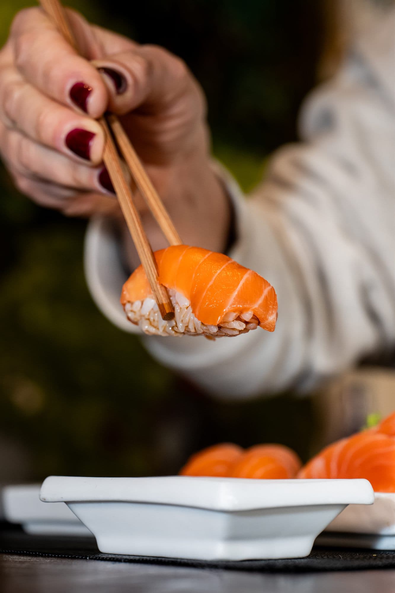 Un nigiri di salmone preso con le bacchette