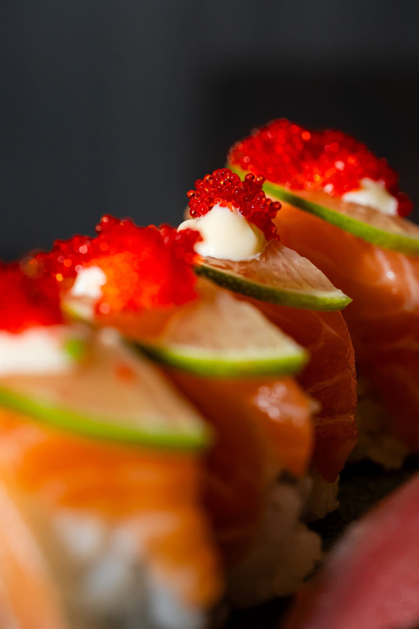 Uramaki con salmone, lime e uova di pesce in primo piano