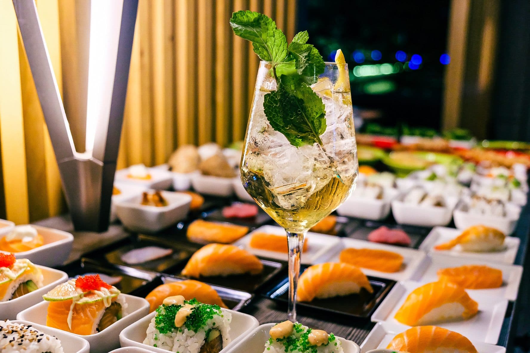 Buffet con nigiri, ciotoline e un calice di vino bianco