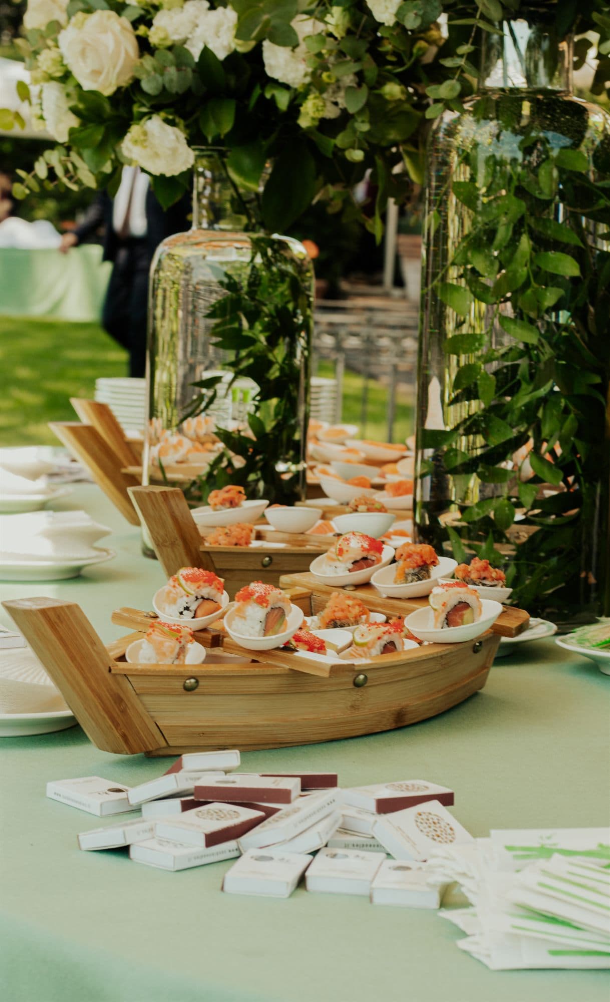 Allestimento per un evento con composizioni floreali e barca di sushi