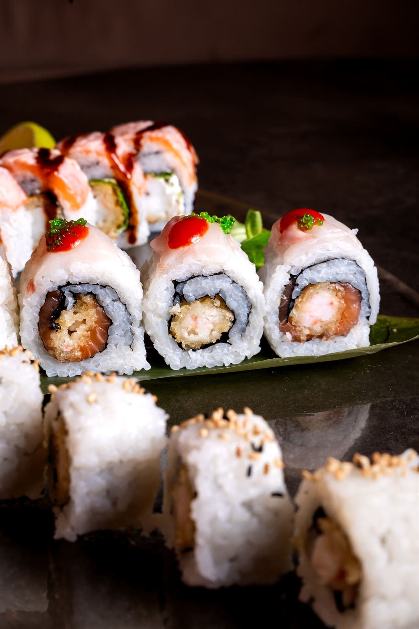 Uramaki con salmone e salse serviti su foglia