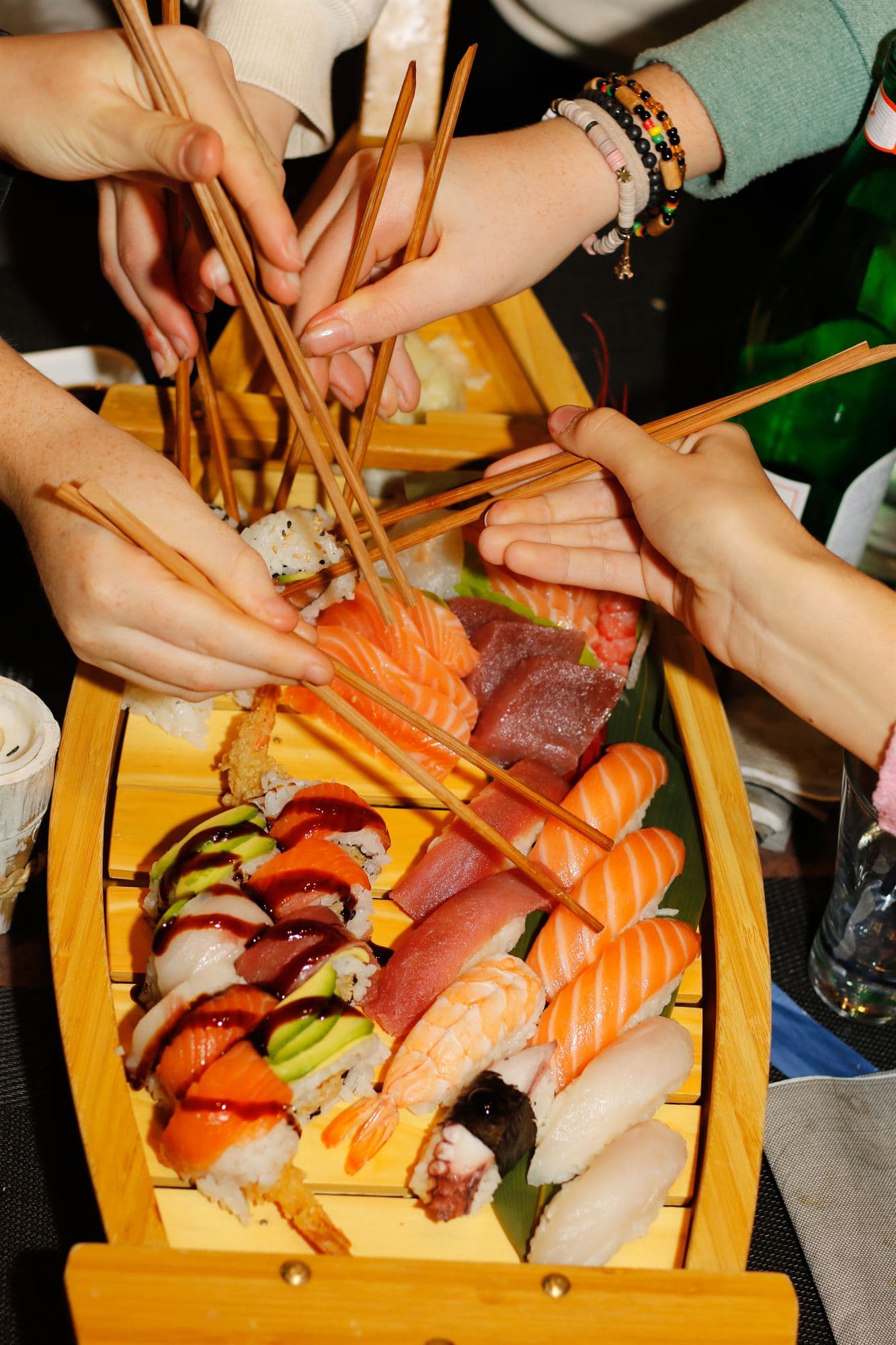 Piu’ persone prendono con le bacchette da una barca di sushi