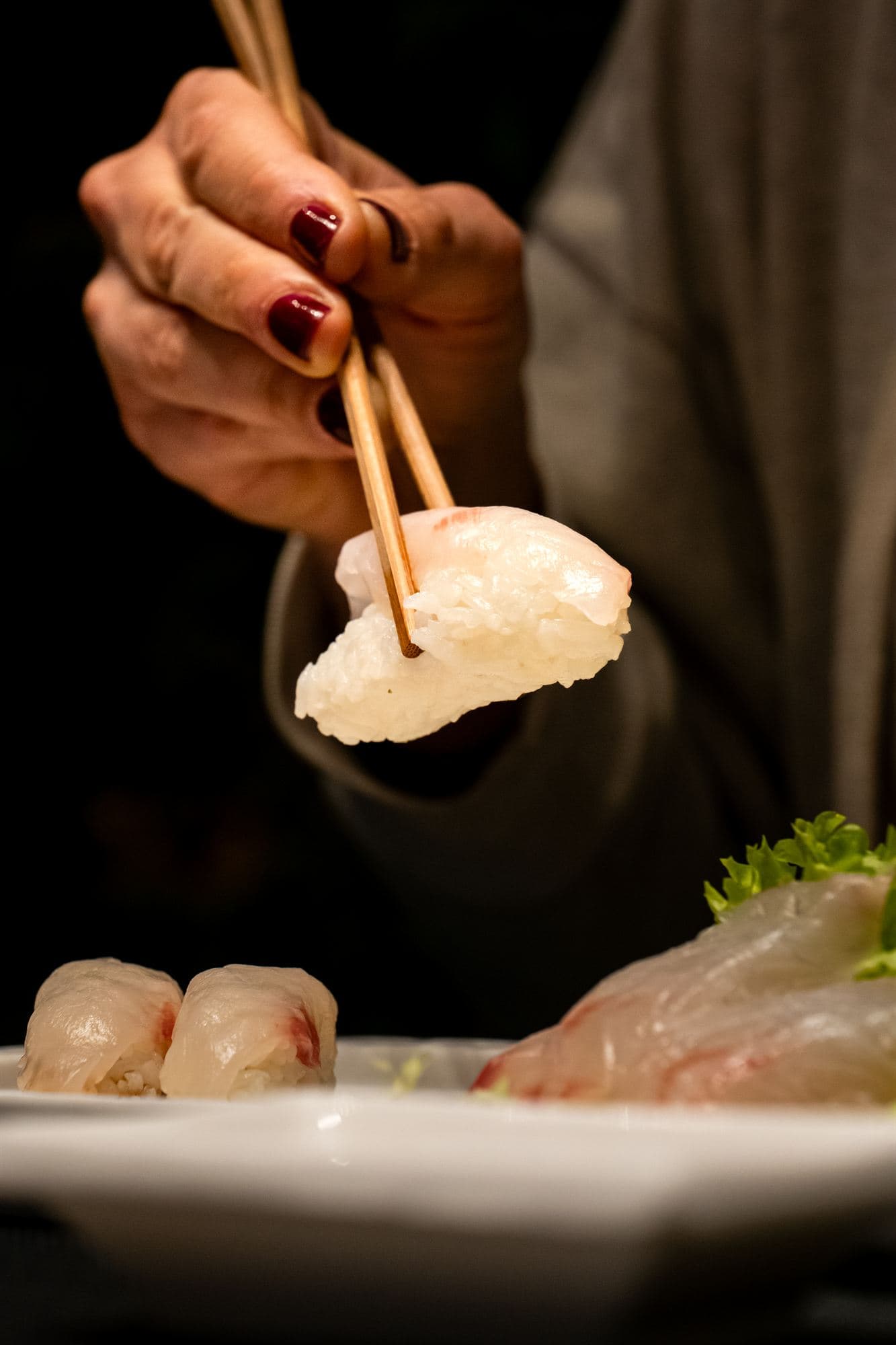 Un nigiri di gambero preso con le bacchette