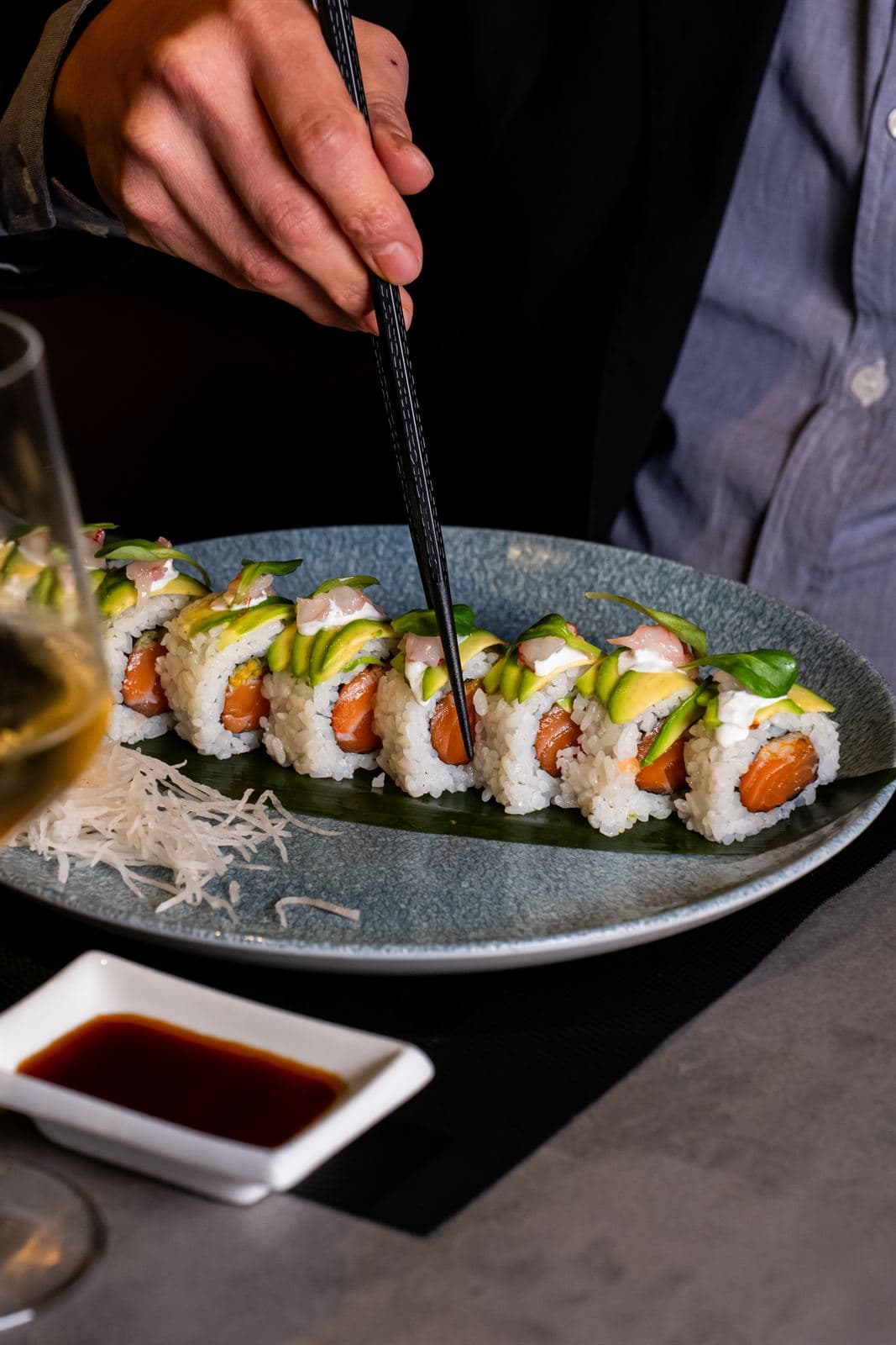 Uramaki di salmone e avocado presi con le bacchette