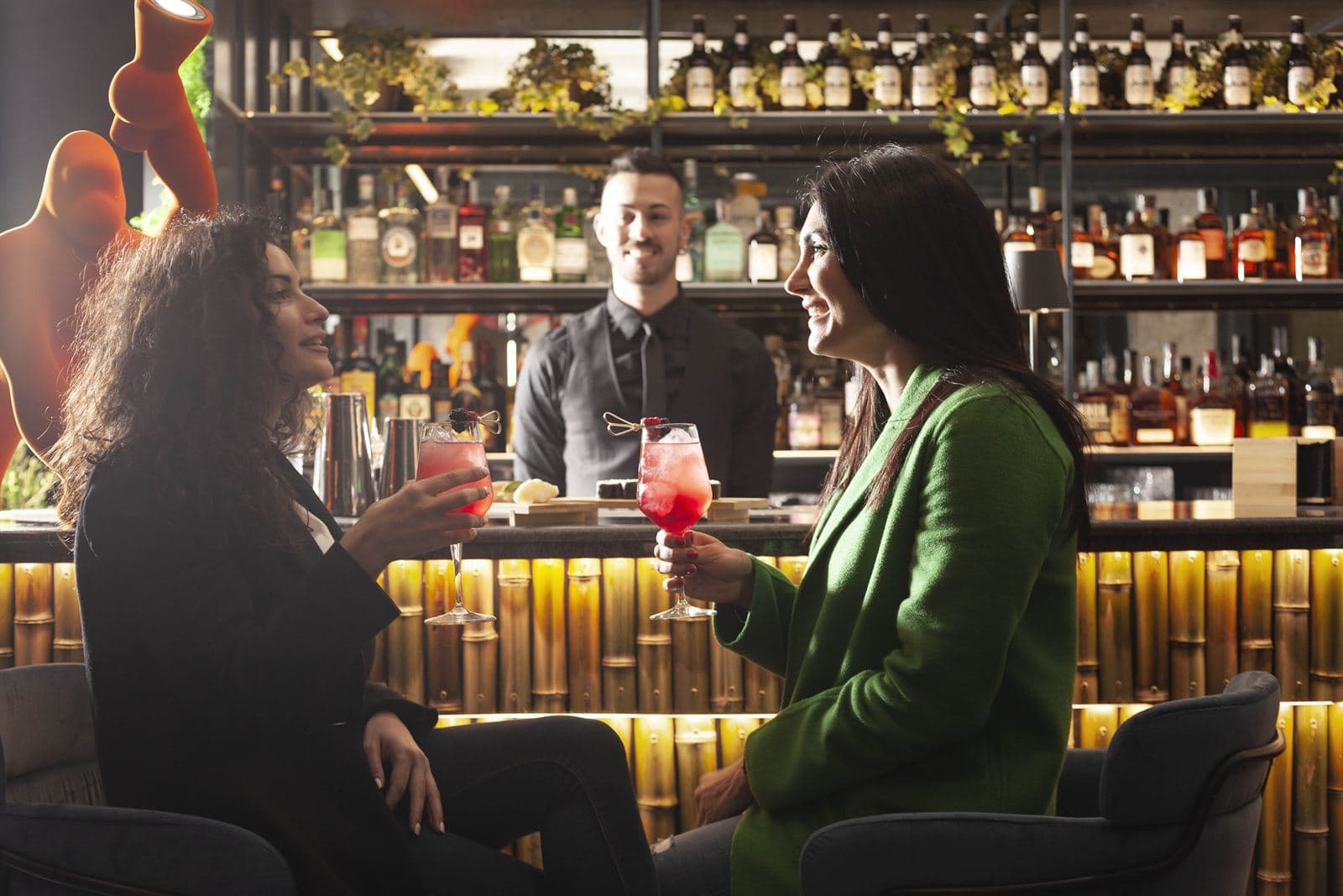 Tre persone brindano al bancone bar con il barman